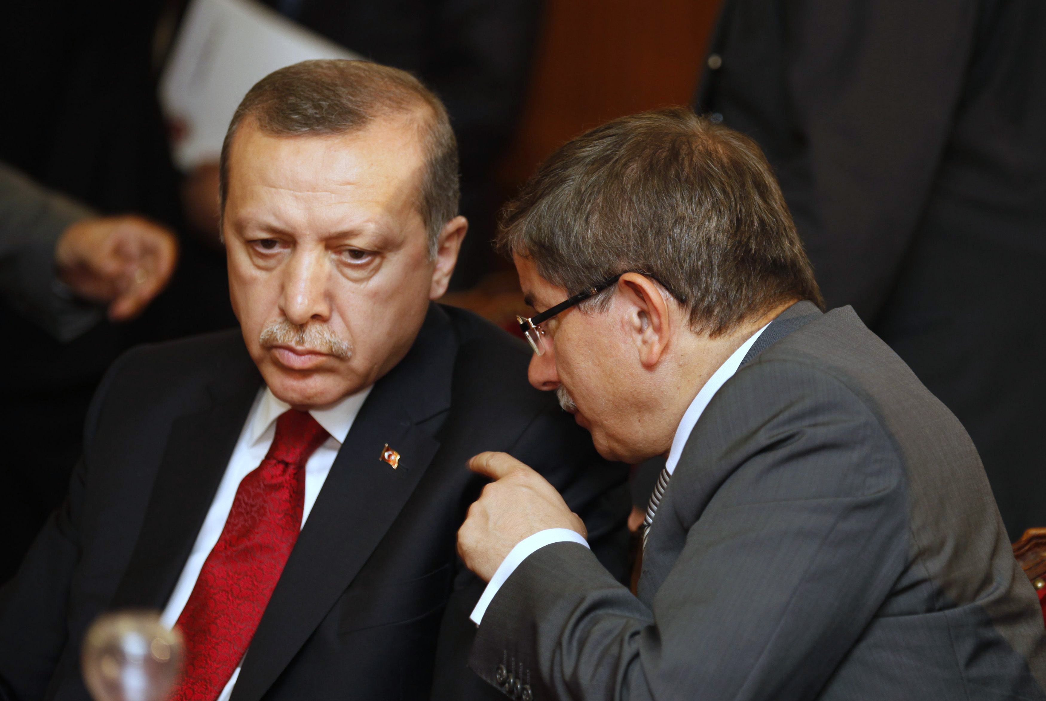 Turkey's FM Davutoglu speaks with Turkish PM Erdogan during a meeting at the government palace in Tunis