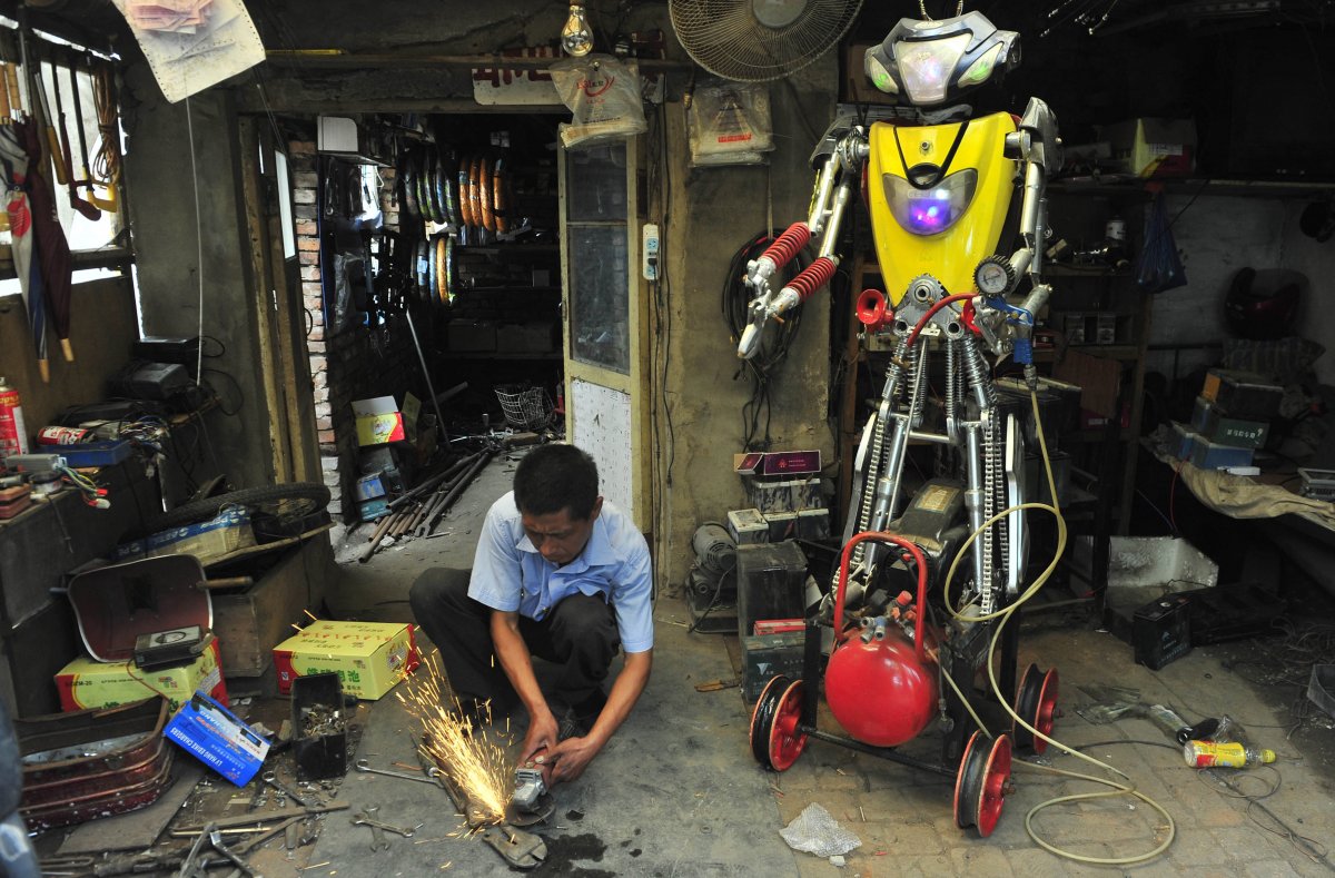 a-49-year-old-electric-bike-mechanic-who-identified-himself-only-as-wu-welds-a-component-to-fit-onto-his-newly-made-robot-r-at-his-repair-shop-in-shenyang-liaoning-province-june-25-2012