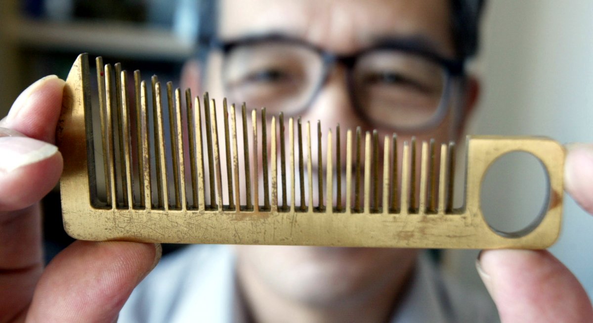 han-yuzi-63-inventor-holds-up-one-of-his-creations-a-hair-comb-that-doubles-as-a-small-hand-held-musical-instrument-in-guangzhou-the-capital-of-chinas-guangdong-province-september-13-2003