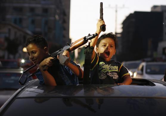 Palestinian children hold guns as they celebrate with others what they said was a victory over Israel, following a ceasefire in Gaza City