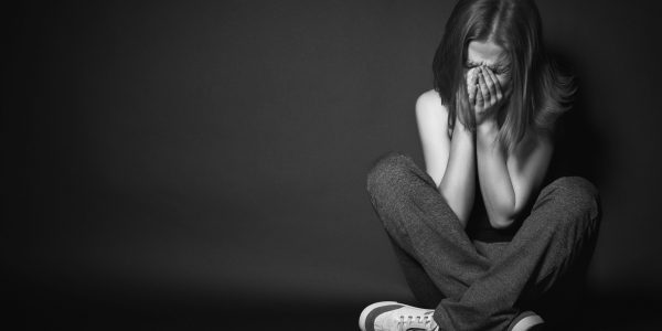 woman in depression and despair crying on black dark