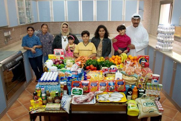KUW03.0001.xxf1rw (MODEL RELEASED IMAGE) The Al Haggan family and their two Nepali servants in the kitchen of their home in Kuwait City, Kuwait, with one week’s worth of food. Standing between Wafaa Abdul Aziz Al Qadini, 37 (beige scarf), and Saleh Hamad Al Haggan, 42, are their children, Rayyan, 2, Hamad, 10, Fatema, 13, and Dana, 4. In the corner are the servants, Andera Bhattrai, 23 (left), and Daki Serba, 27. Cooking methods: gas stoves (2), microwave. Food preservation: refrigerator-freezer. /// The Al Haggan family is one of the thirty families featured in the book Hungry Planet: What the World Eats (p. 196). Food expenditure for one week: $221.45 USD. (Please refer to Hungry Planet book p. 197 for the family’s detailed food list.)
