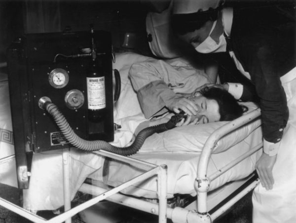 July 1939:  In an effort to make childbirth as painless as possible, a patient inhales analgesia during labour whilst a nurse looks over her.  (Photo by London Express/Getty Images)